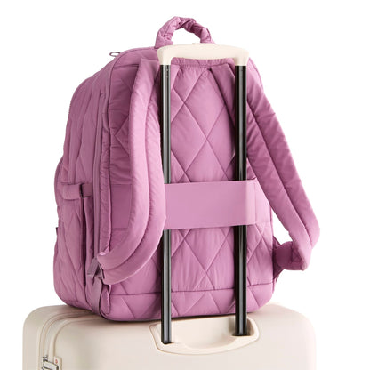 Purple quilted backpack attached to a suitcase on a white background